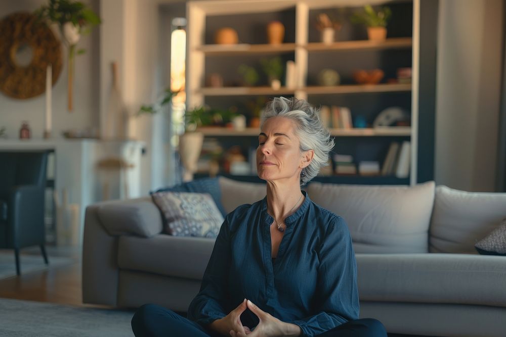 Middle aged woman meditating at home with eyes closed meditation mental living.