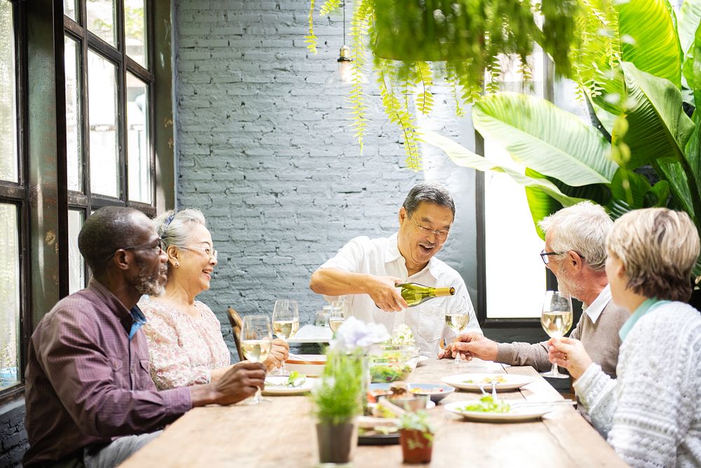 Diverse group of elderly friends, Asian man, Asian woman, African American man, enjoying a meal together. Elderly friends…