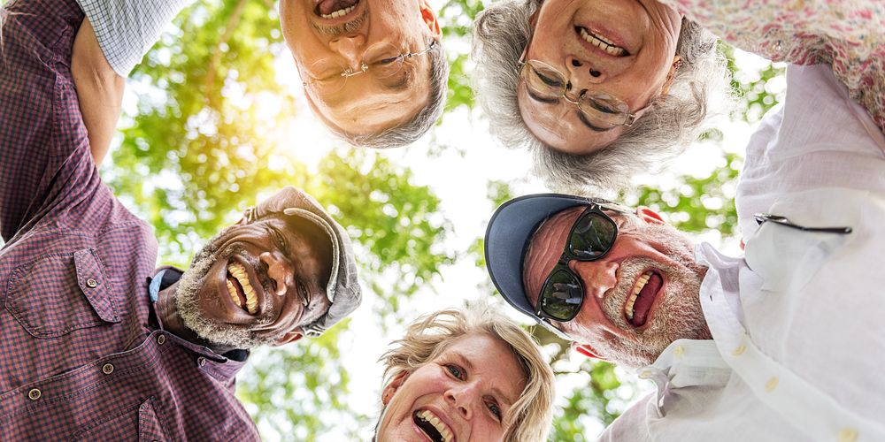 Group of diverse elderly friends, group hug, smile and laugh outdoors. Happy elderly diverse friends group hug outdoors…