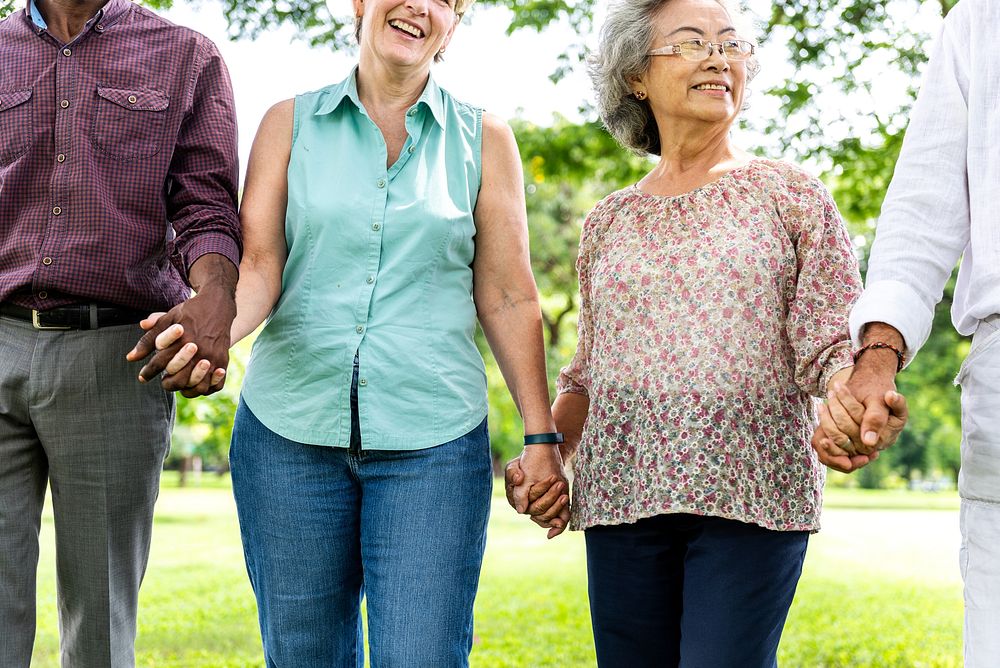 Group of diverse senior friends holding hands in park, unity and support. Diverse people senior group holding hands in…