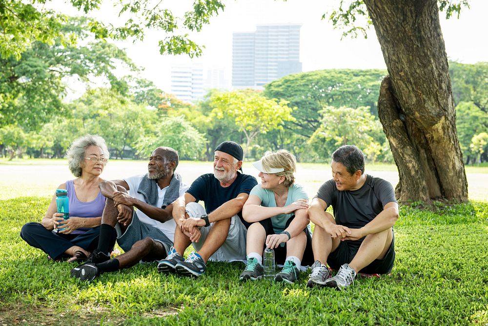 Group of diverse happy senior friends chat in park, green grass lawn. Diverse senior friends enjoy healthy relax lifestyle…