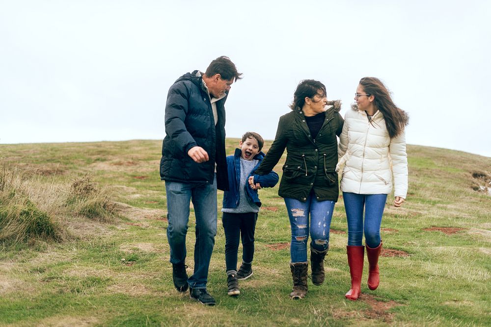 Happy Caucasian family holding hands outdoors, mother, father, son, and daughter. Family holding hands enjoying nature.…