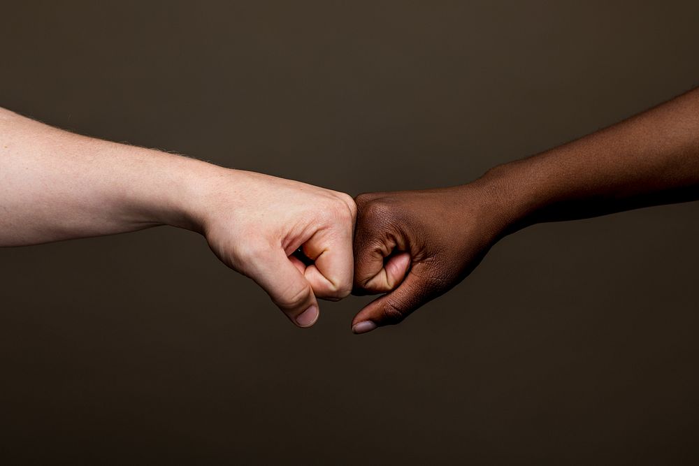 Close-up of a fist bump between diverse ethnic hands. Fist bump unity, friendship, and teamwork. Unity and friendship…