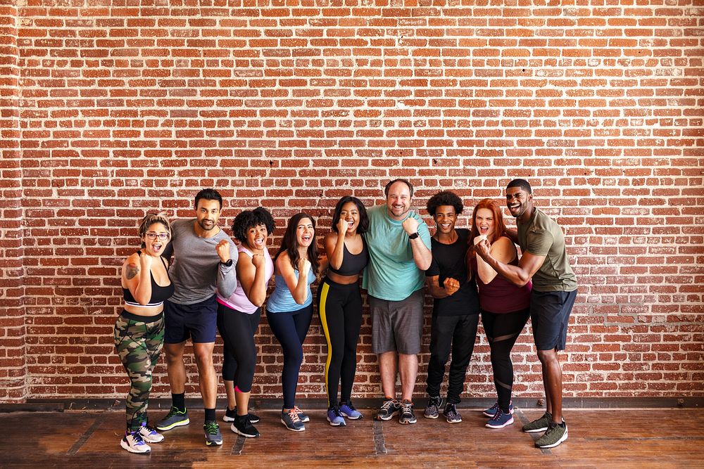 Diverse group of men and women at a gym. Standing confident by brick wall. Confident and strong, men and women in a fitness…