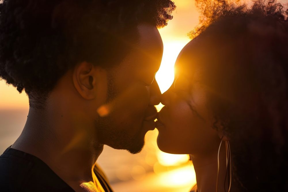 Black couple outdoors kissing sunset.