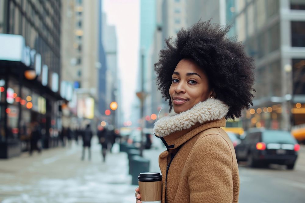 An african american woman walking with a coffee on a city sidewalk adult smile architecture.
