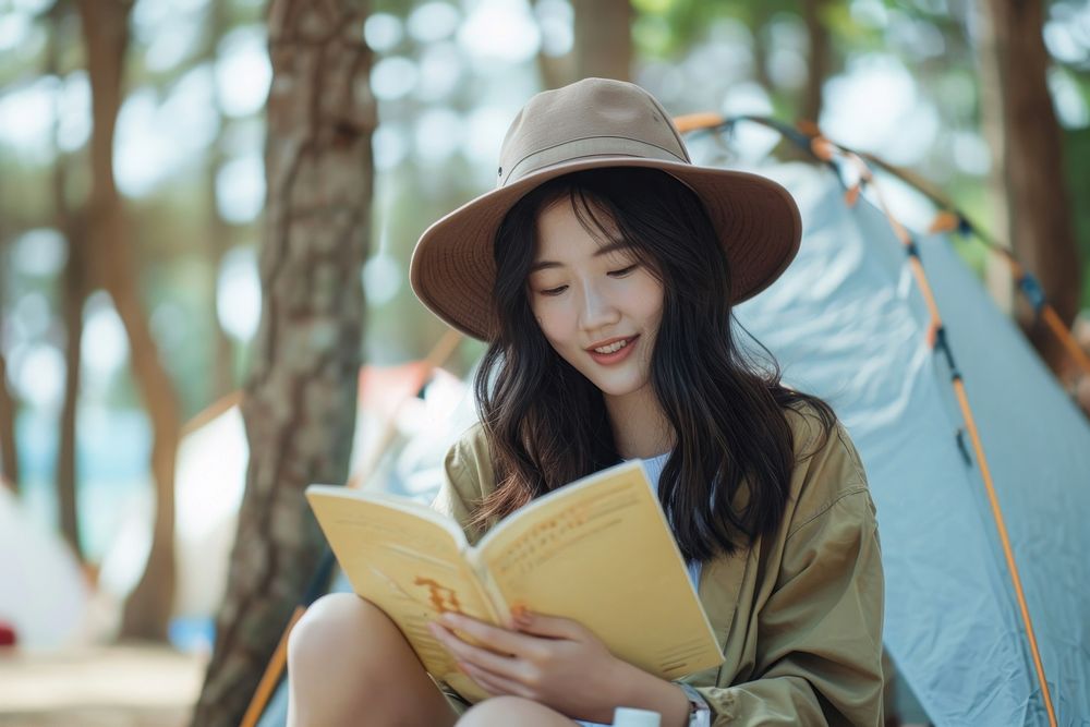 Asian influencer recording video while read a book publication outdoors reading.