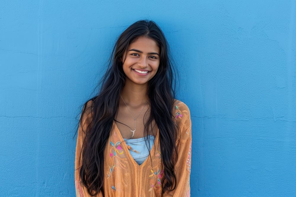 Indian american woman smile blue wall.