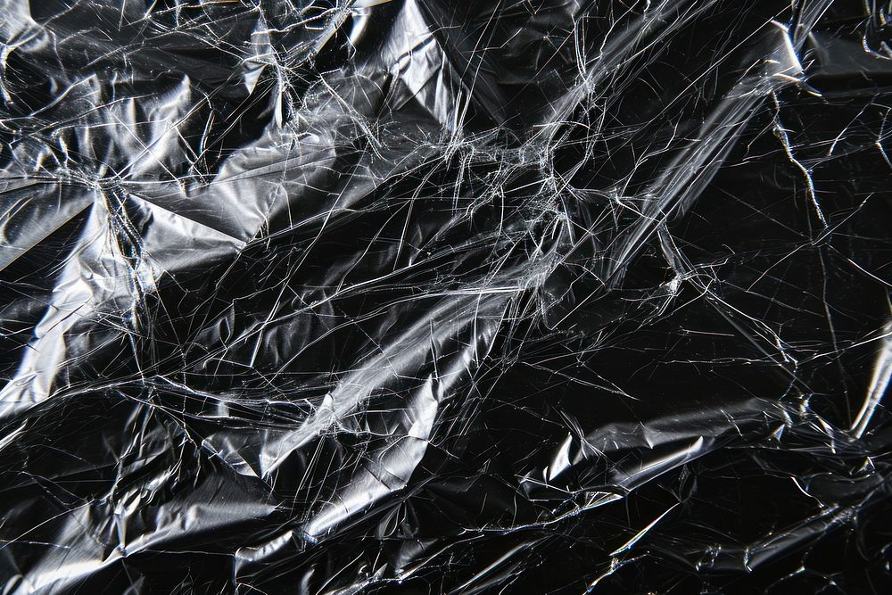 Plastic wrap with hole tear backgrounds black monochrome.