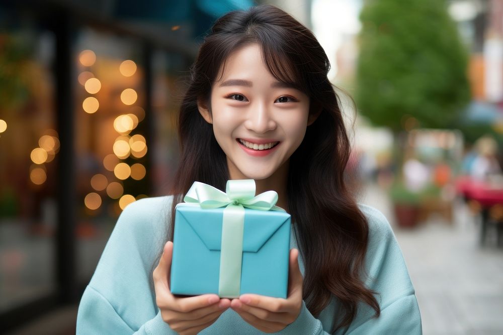 Japanese girl holding a gift box looking happy and fun smile architecture celebration. AI generated Image by rawpixel.