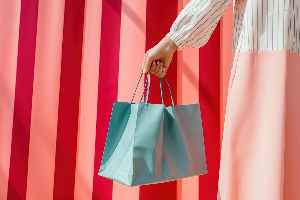 Hand holding a shopping bag handbag consumerism accessories.