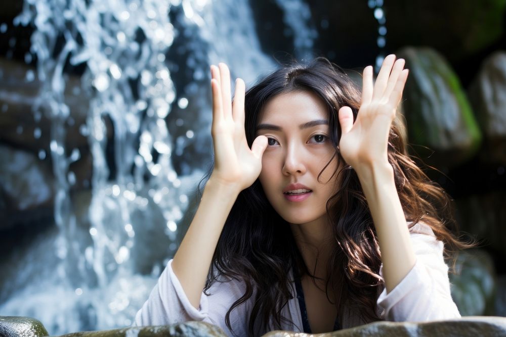 East Asian Cooling Off in a Waterfall Oasis waterfall portrait worried. AI generated Image by rawpixel.