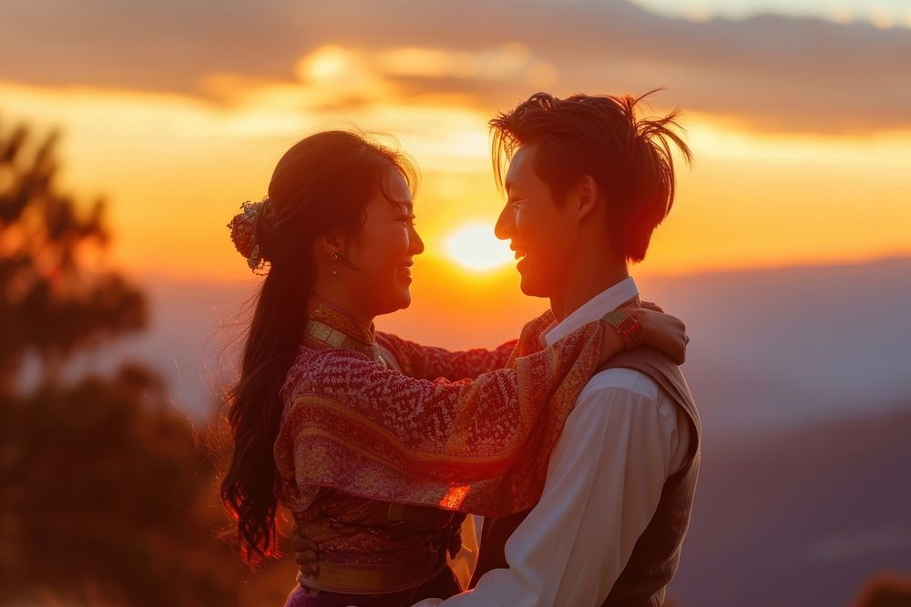 Bhutanese couple dancing outdoors smiling sunset.