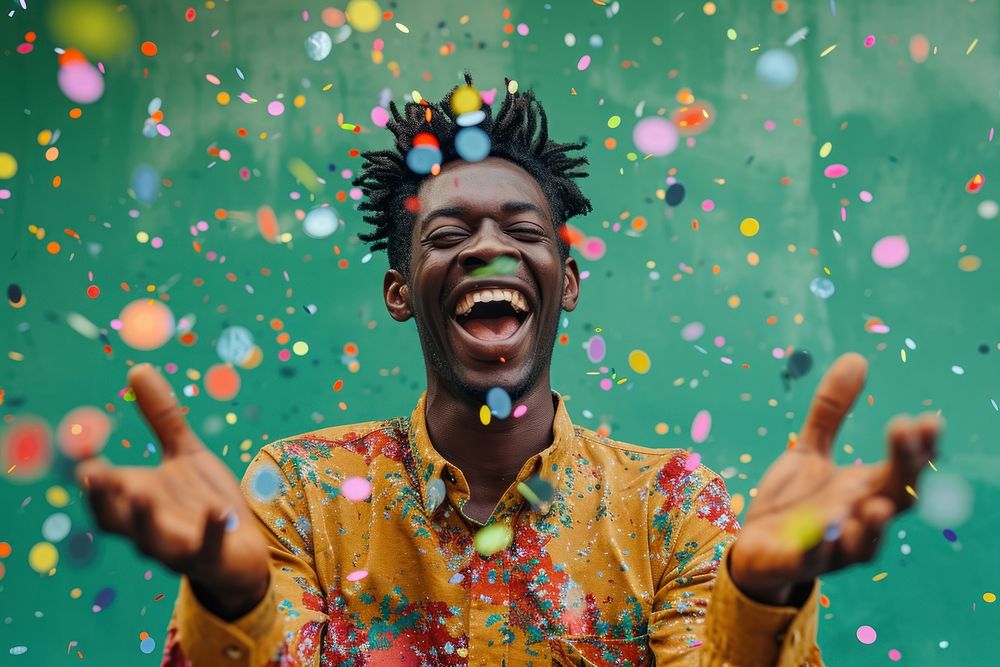 Cheerful black man with confetti enjoying cheerful laughing celebration.
