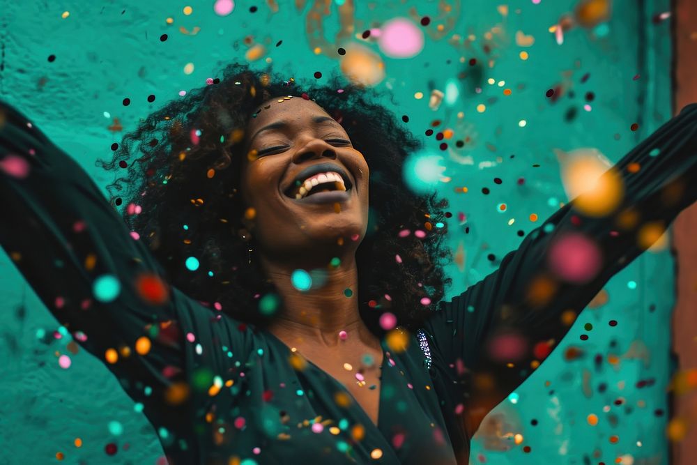 Cheerful black woman with confetti enjoying cheerful laughing illuminated.