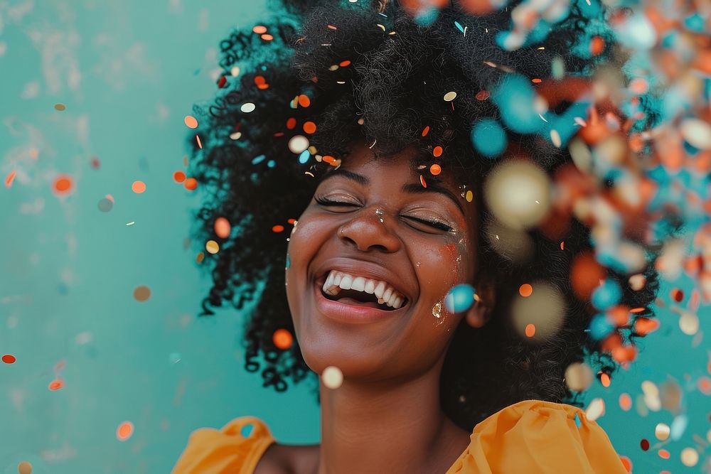 Cheerful black woman with confetti enjoying cheerful laughing smile.