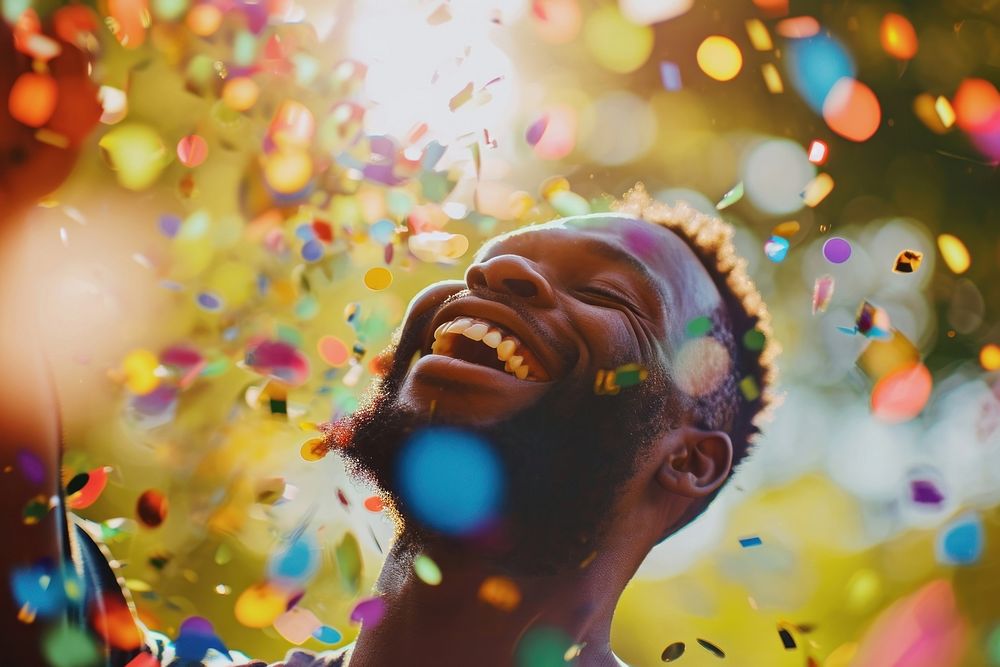 Cheerful black man with confetti enjoying cheerful laughing smile.