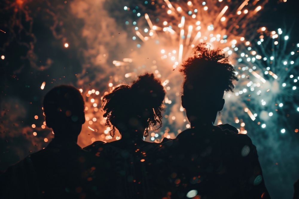 Fireworks with silhouettes of black people light adult togetherness.