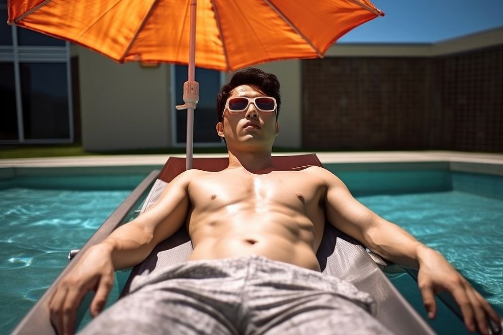 East asian men sunbathing sunglasses poolside.