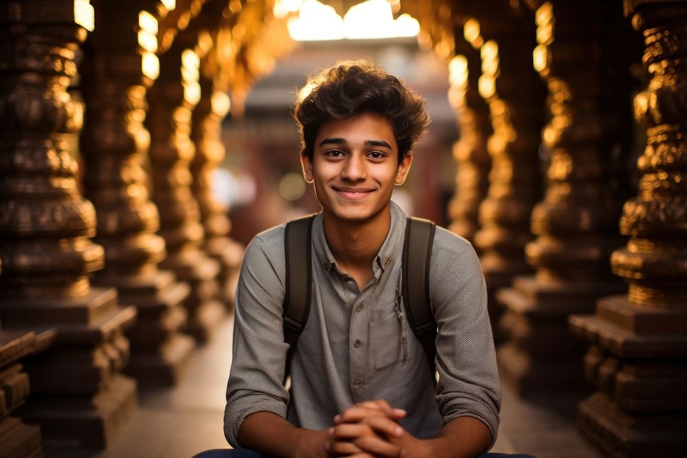 Indian teen age man temple smile cross-legged.