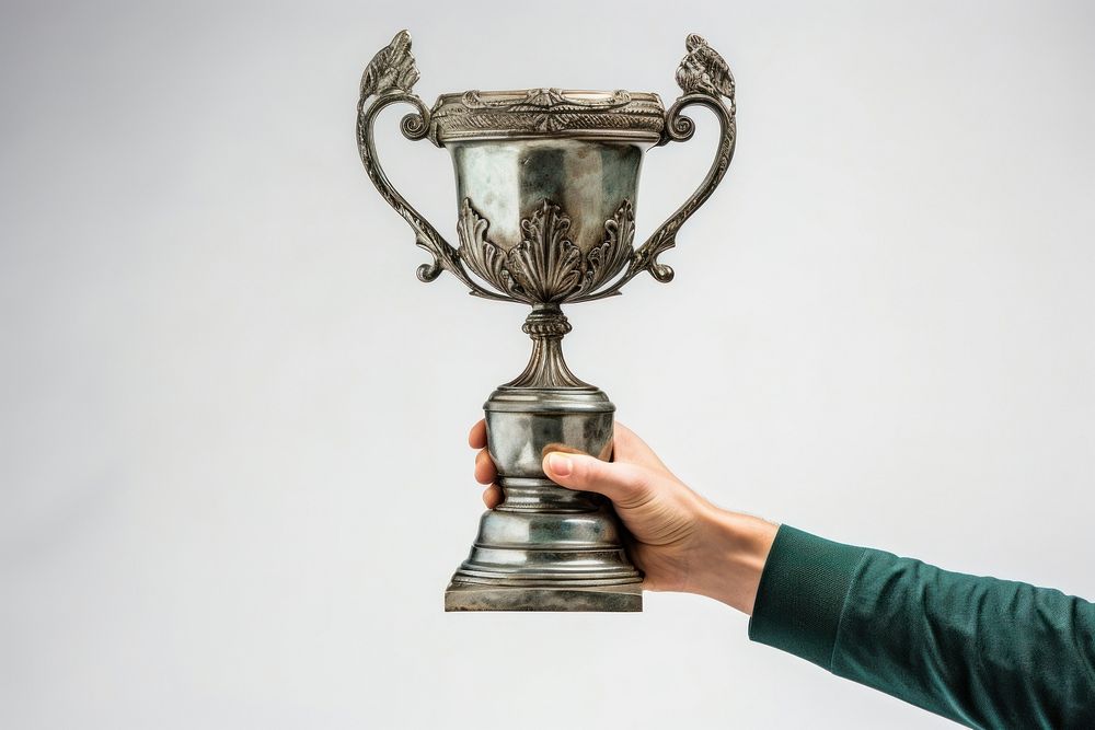 A hand holding up an aged trophy achievement innovation midsection.