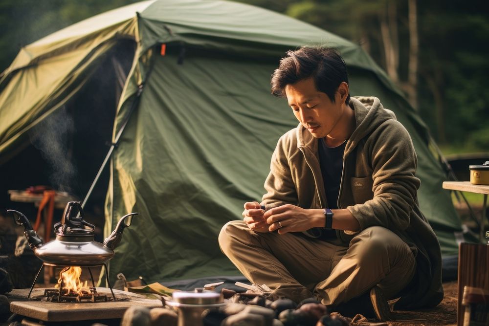 East asian man camping outdoors relaxation.
