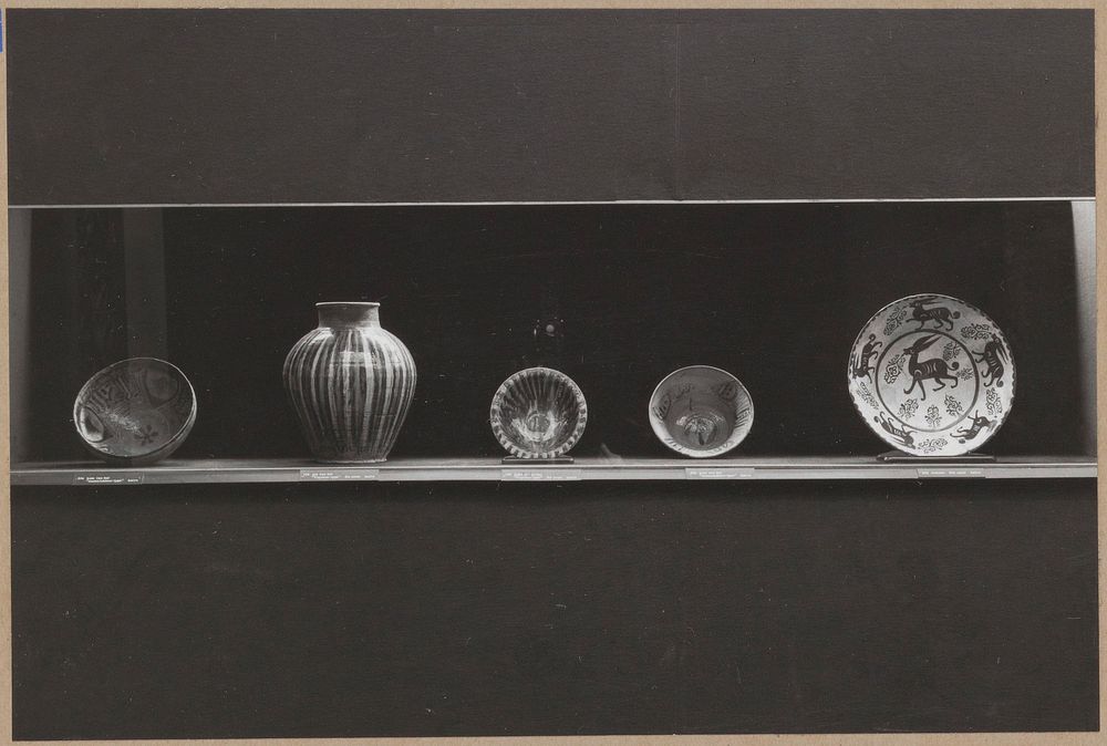 Vitrine met keramiek, waaronder rechts een kom met de afbeelding van een haas met een klaverblad in de bek (c. 1960) by…