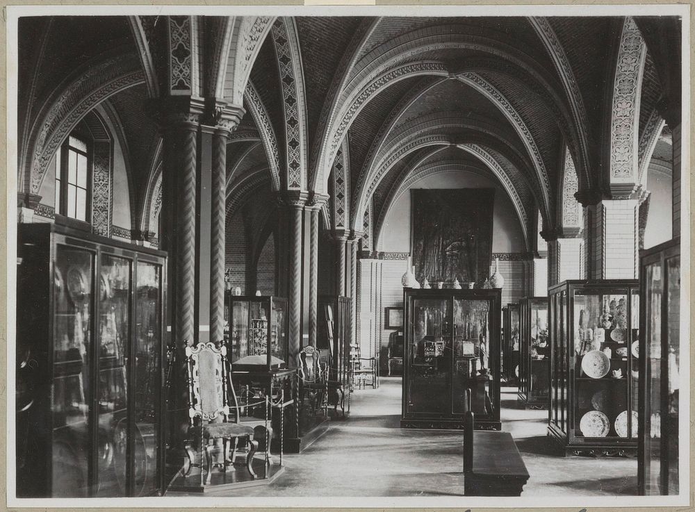 Zaal met gedecoreerde pilaren en bogen, een wandtapijt, meubels en vitrines met keramiek (c. 1890) by Rijksmuseum Afdeling…