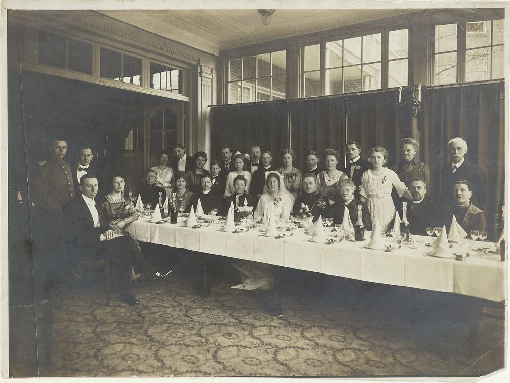 Bruidspaar en gasten aan en om tafel (1918) by anonymous