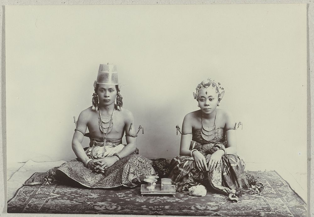 Studioportret van een zittende jonge Javaanse man en vrouw dragend een batik sarong (c. 1870 - c. 1912) by Kassian Céphas