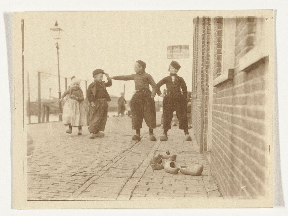 Kinderen in klederdracht in Volendam, op de voorgrond enkele klompen (c. 1900 - c. 1910) by G Hidderley