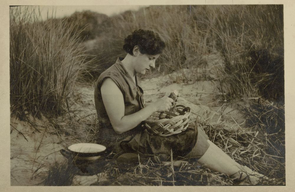 Vrouw schilt aardappel in de duinen (c. 1920 - c. 1935) by anonymous