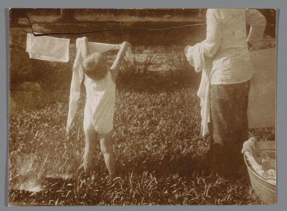 Kind helpt met het ophangen van de was (c. 1920 - c. 1935) by anonymous
