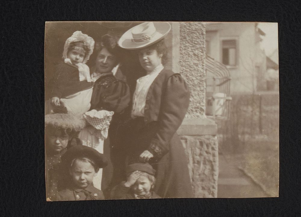Groepsportret van twee vrouwen en vier kinderen voor een huis (1895 - 1915) by anonymous