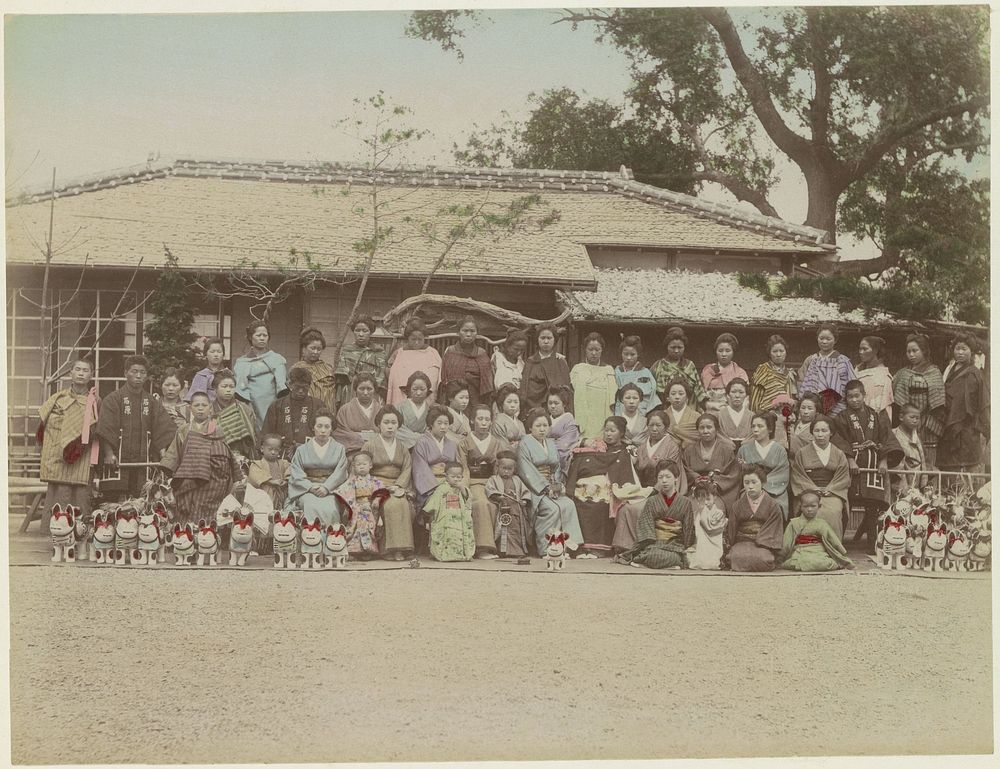 Groepsportret van Japanse vrouwen, mannen en kinderen met hondenbeelden voor een gebouw (c. 1870 - c. 1900) by anonymous