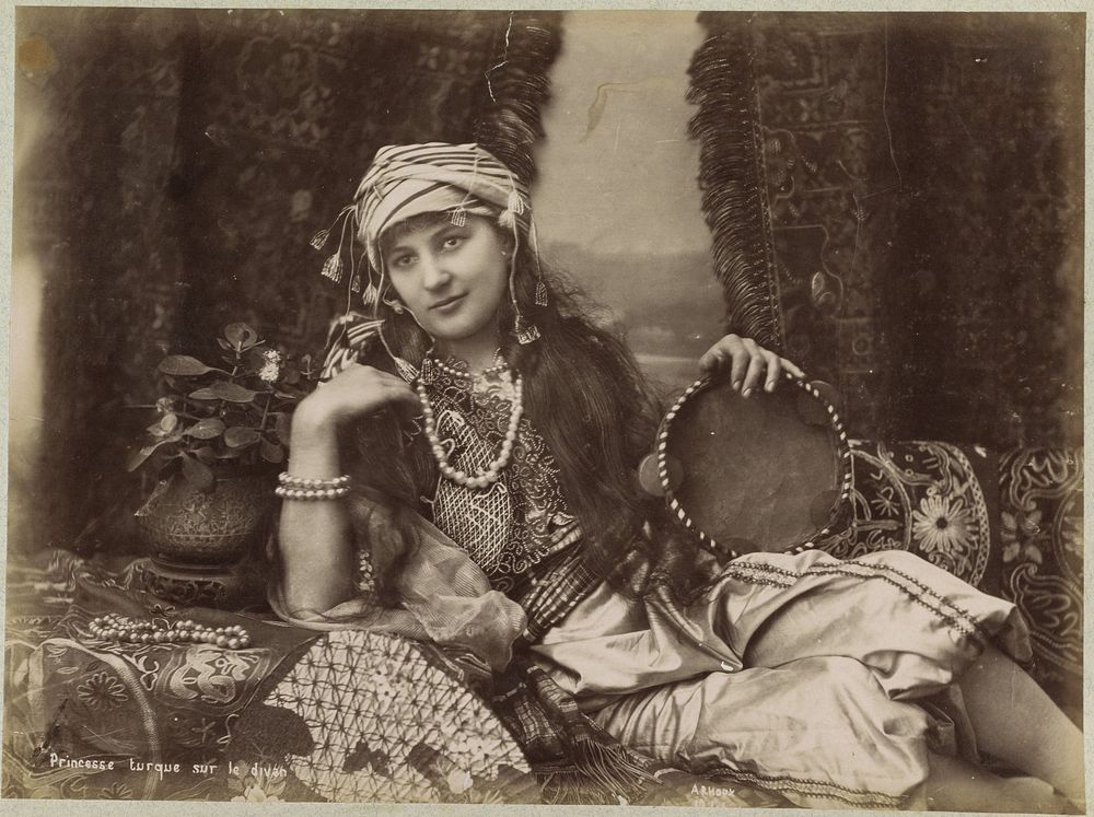 Portret van een Turkse vrouw met tamboerijn in de hand, liggend op een divan (c. 1870 - c. 1891) by Hippolyte Arnoux