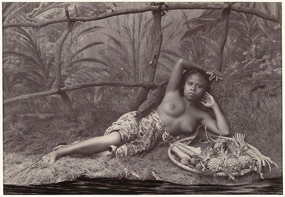 Portret van een onbekende Indonesische halfnaakte vrouw, liggend met een fruitmand in een decor (1880 - 1900) by anonymous