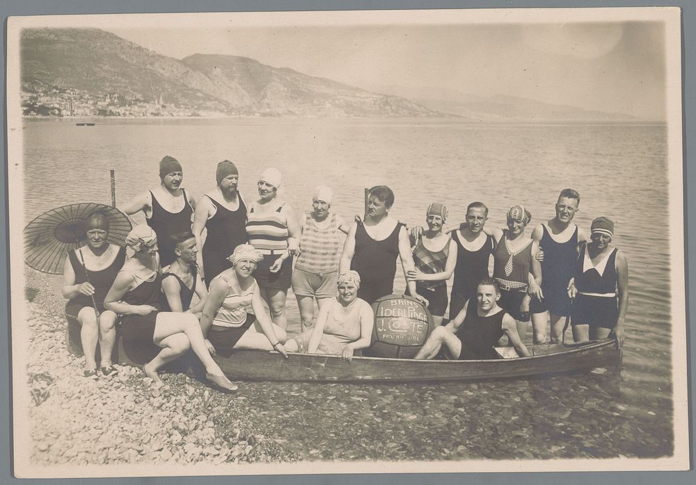 Groepsportret van een onbekend gezelschap rond een boot op een kiezelstrand (c. 1920 - c. 1930) by anonymous