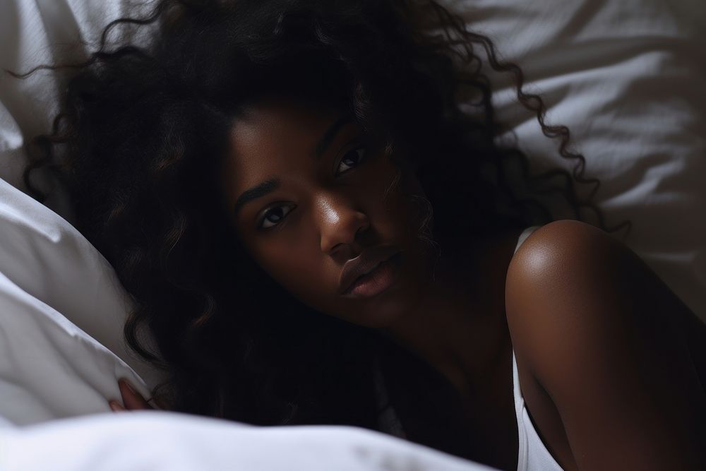 The black woman is sitting on the side of bed portrait head contemplation.