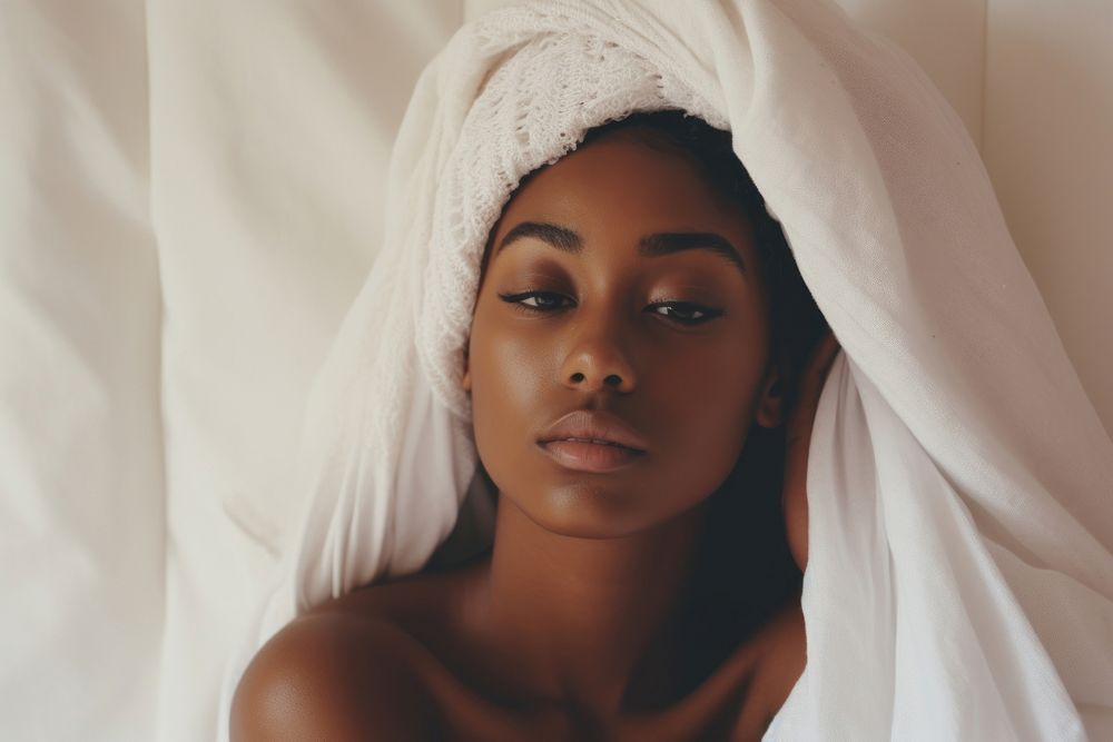 The black woman is sitting on the side of bed portrait white skin.