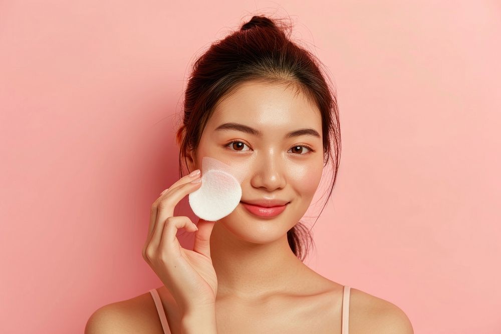 Cleansing her face skin with a cotton pad portrait adult woman.