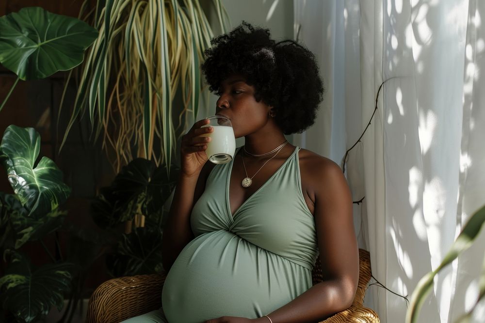 Black Woman drinking milk during her pregnancy sitting adult woman. AI generated Image by rawpixel.