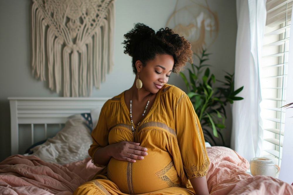 Pregnant black woman touching her belly while sitting on her bed adult anticipation accessories. AI generated Image by…
