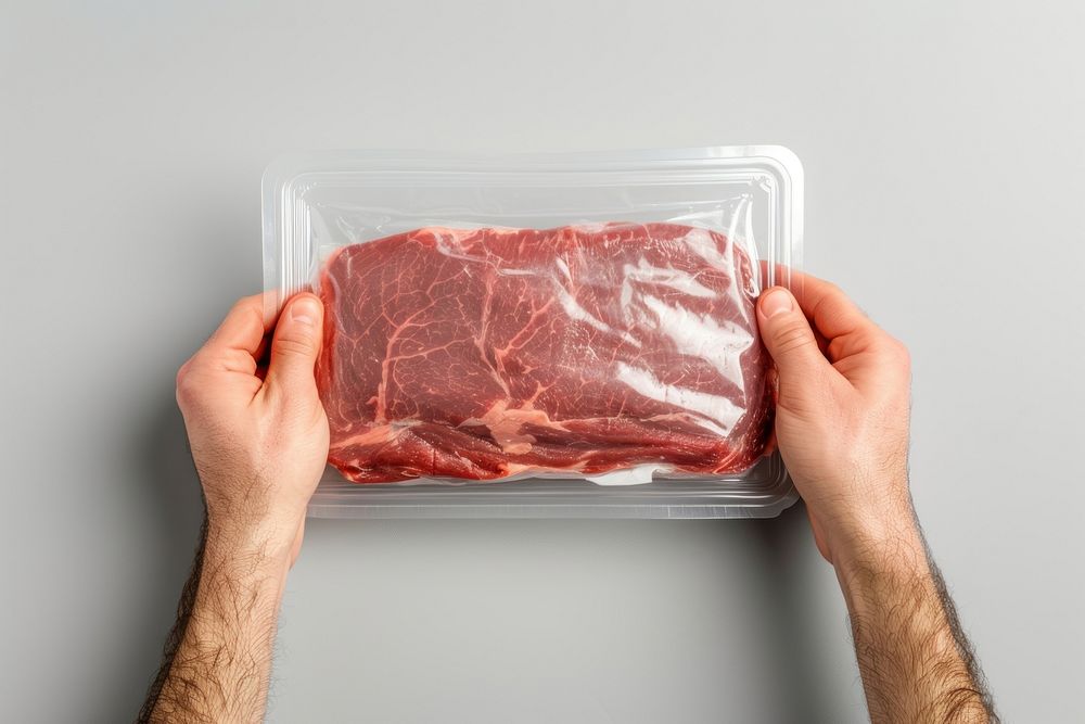 Close-up hand carry choose beef plastic package and cover with blank label adult meat food.
