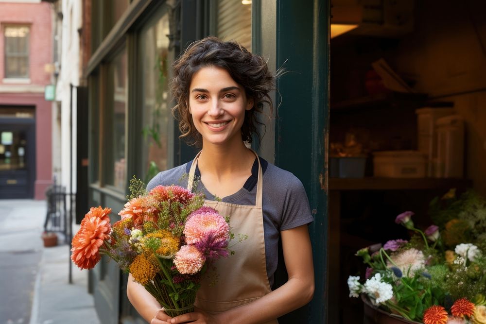 Woman in apron holding a bouquet of flowers smile store plant.