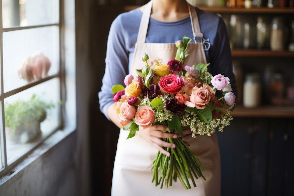 Woman in apron holding a bouquet of flowers plant adult store.