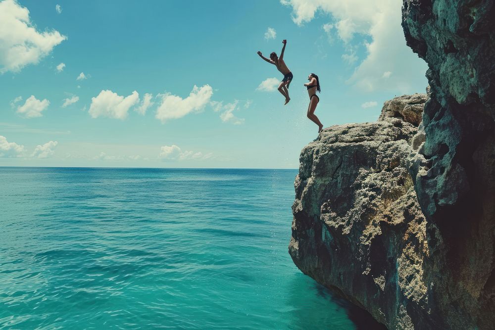 Young active man and woman diving from high cliff ocean water land.