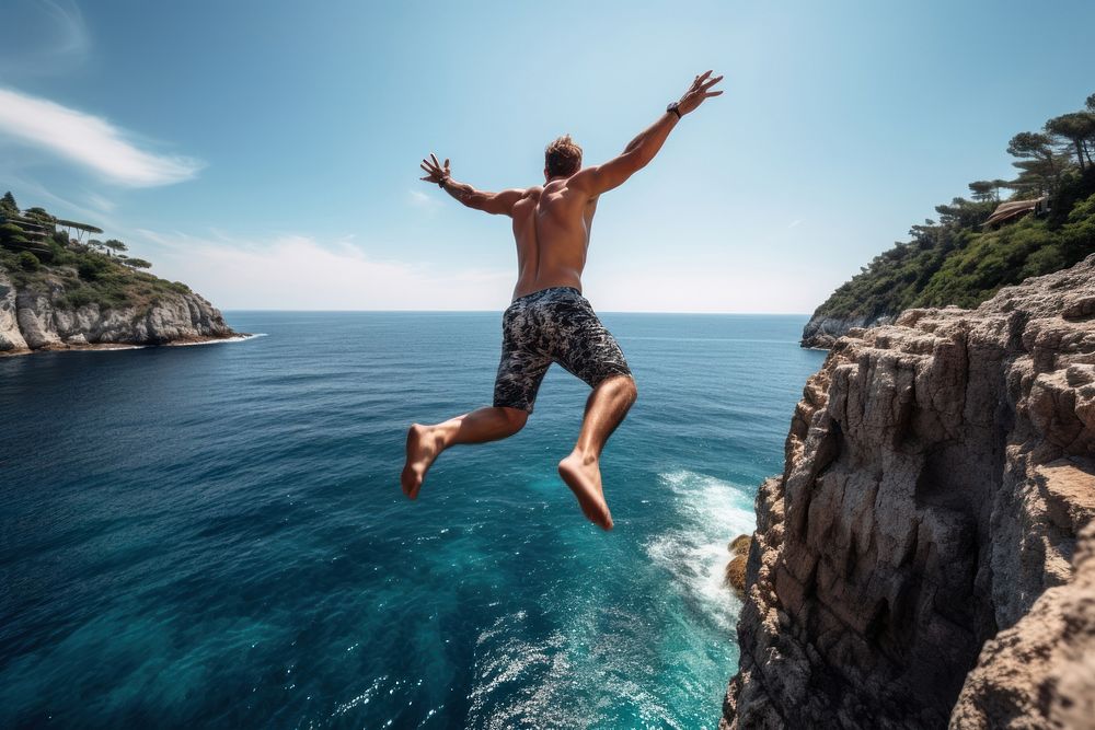 Athletic young man jumping off a rocky diving vacation summer.