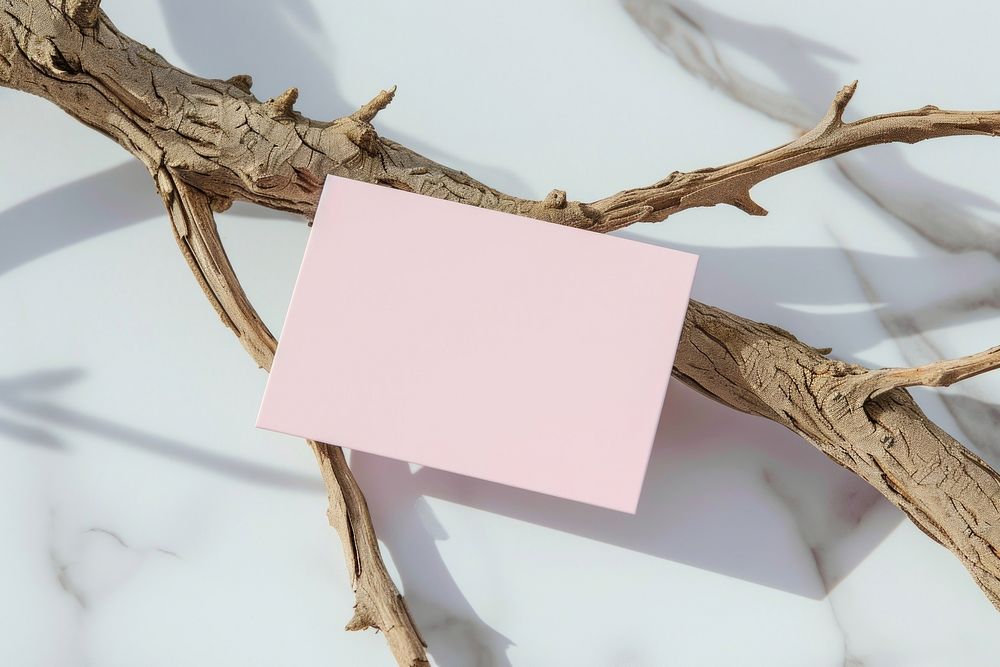 Business card on white marble wood branch outdoors.