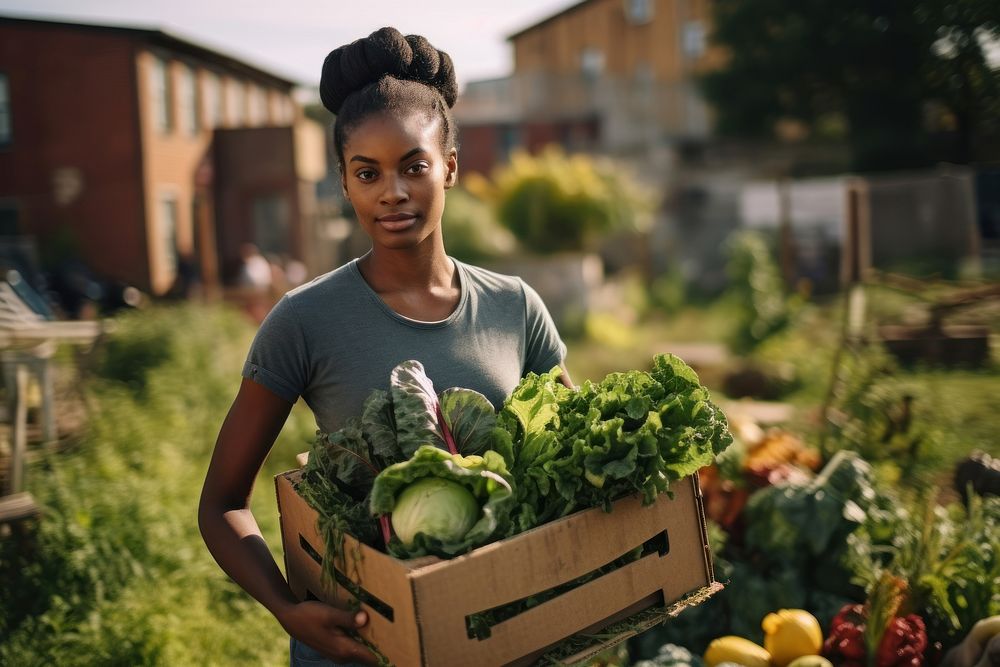 Young woman carrying a box with vegetables portrait garden green.